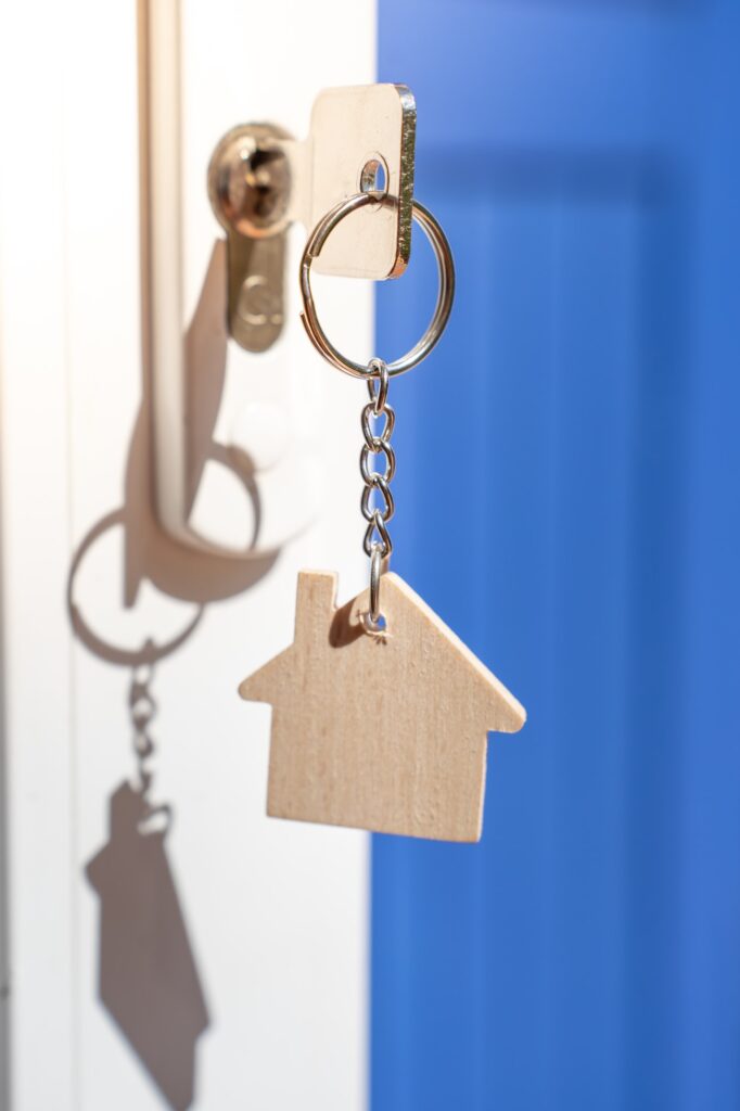 Opening door to a new home with key and home shaped keychain. Property and new home concept