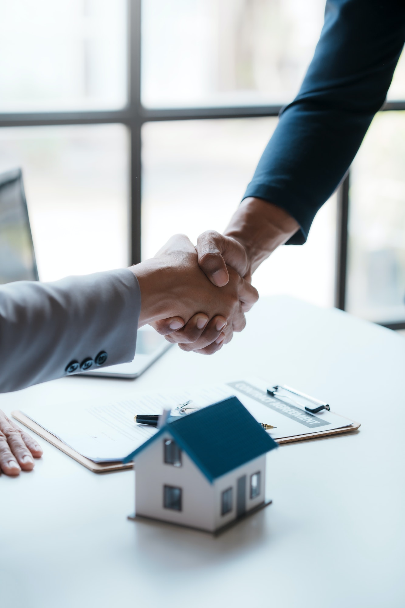 Real estate agent shakes hands with a client to sign a home purchase contract congratulating